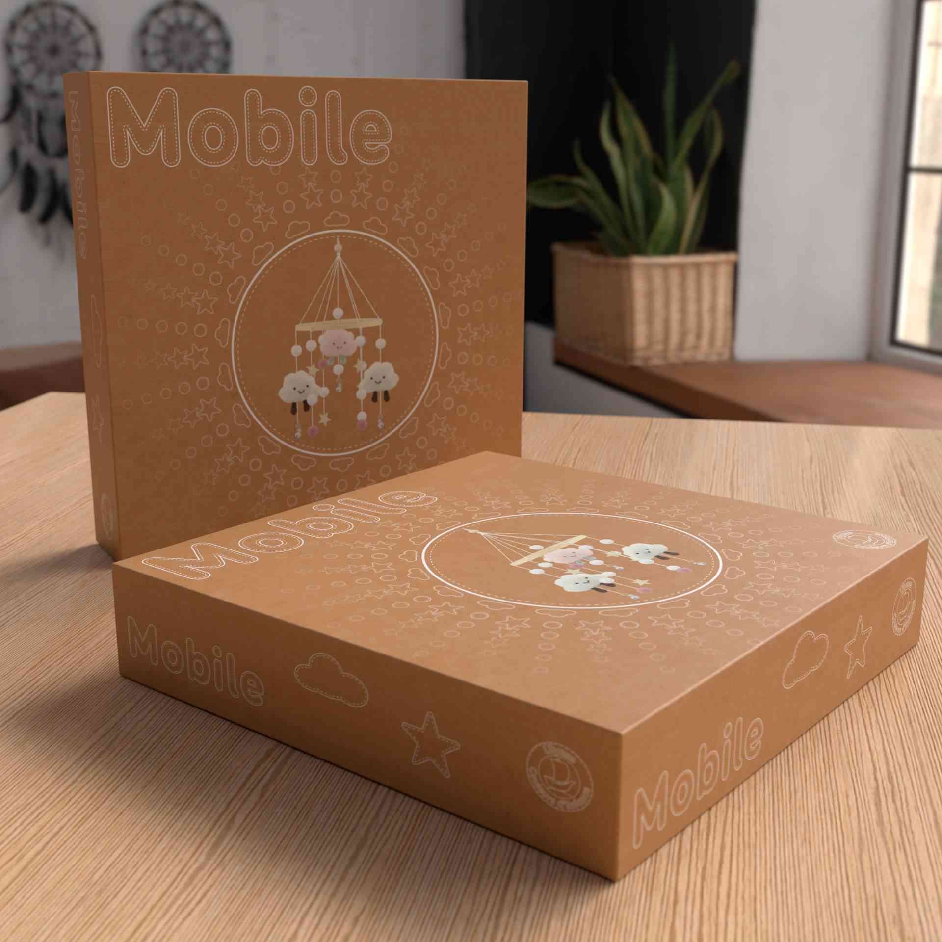 Zwei braune Kartons mit Ulysse Couleurs d'Enfance - Mobile mit rosa Wolken stehen auf einem Holztisch. Ein Karton steht aufrecht, der andere liegt flach. Beide haben eine kreisförmige Abbildung eines Mobiles mit hängenden Schafen, und das Wort „Ulysse Couleurs d'Enfance“ ist in großen Buchstaben aufgedruckt. Diese Mobiles eignen sich perfekt als pädagogisches Spielzeug ab 2. Im Hintergrund steht eine Topfpflanze.