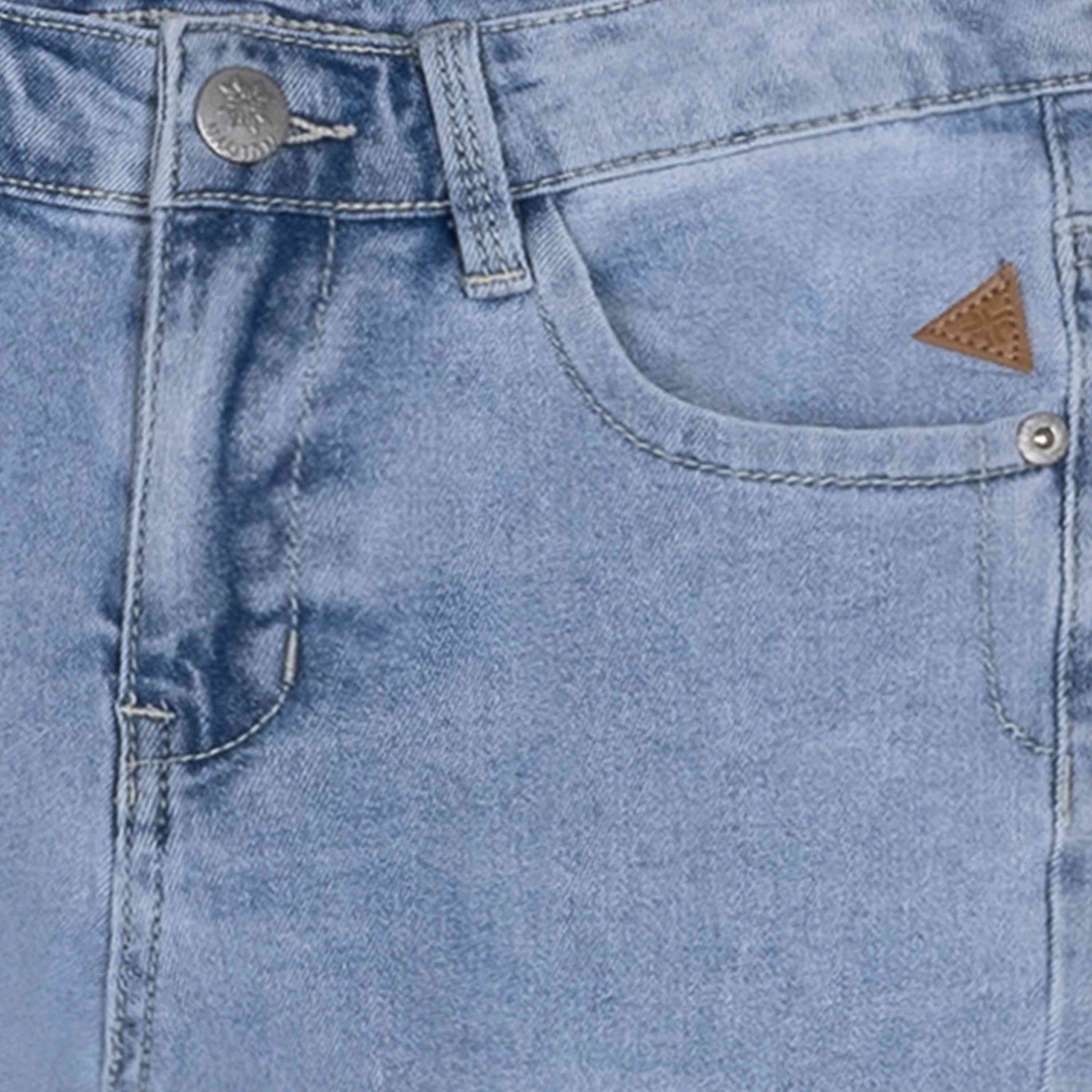Nahaufnahme der Tasche der Indian Blue Jeans – 2142 Bootcut Fit in hellblauem Denim, mit einem kleinen dreieckigen Lederpatch und Metallnieten am Rand. Das Bild zeigt außerdem einen Metallknopf und eine Gürtelschlaufe vom Hosenbund über der Tasche. Marke: Indian Blue Jeans.